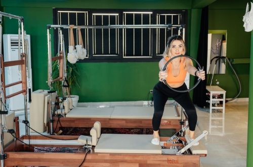 Fitness enthusiast practicing Pilates on a reformer machine in a modern, brightly lit studio.